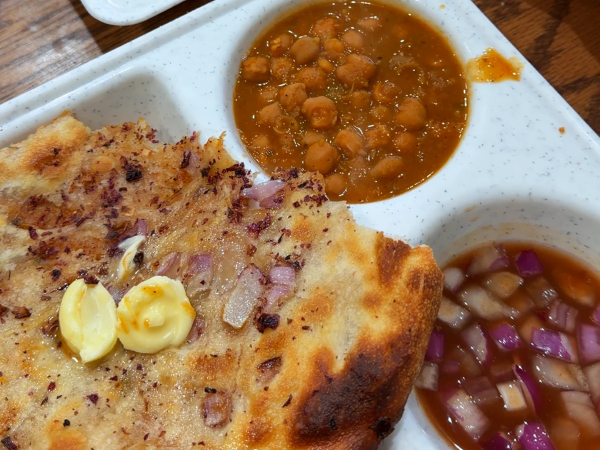 Amritsari kulcha with butter, chickpea curry and chopped onion on a tray